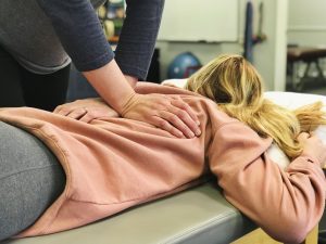 chiropractor adjusting a female patient upper back