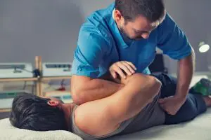 chiropractor adjusting a male patient lower back 