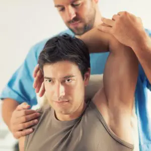 chiropractor helping patient stretch his shoulder