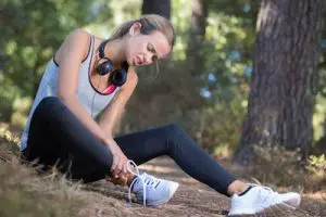 woman holding her ankle from running injury 