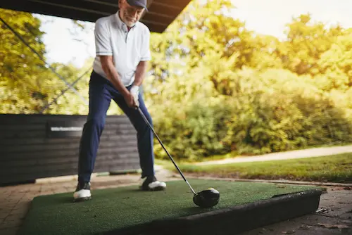 elderly man in golf stance about to swing