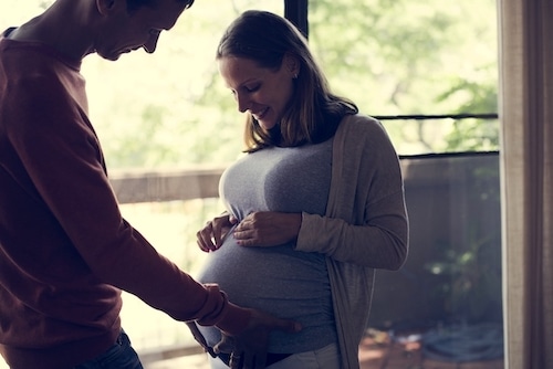 pregnant woman and her husband admiring the baby bump