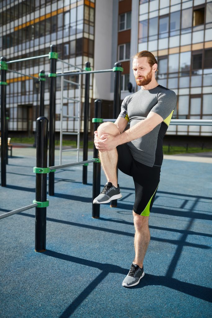 young male stretching his legs before a workout 