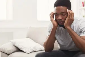 Young man with hands on head due to migraines