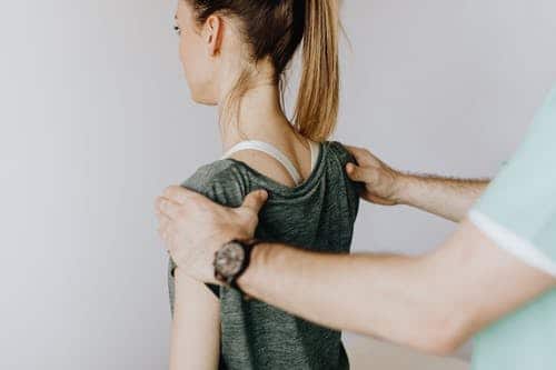 chiropractor guiding a patient to straighten her back