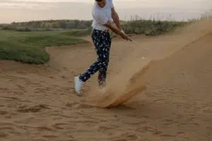 golfer hitting a ball on the sandy side of the golf course