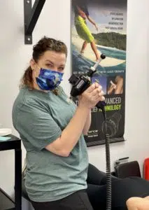 female therapist posing holding a shockwave therapy massage handle