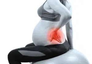 Pregnant woman with back pain and hip pain holds her lower back. 