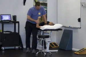 Knoxville chiropractor adjusting a patient's shoulder while laying on a drop table