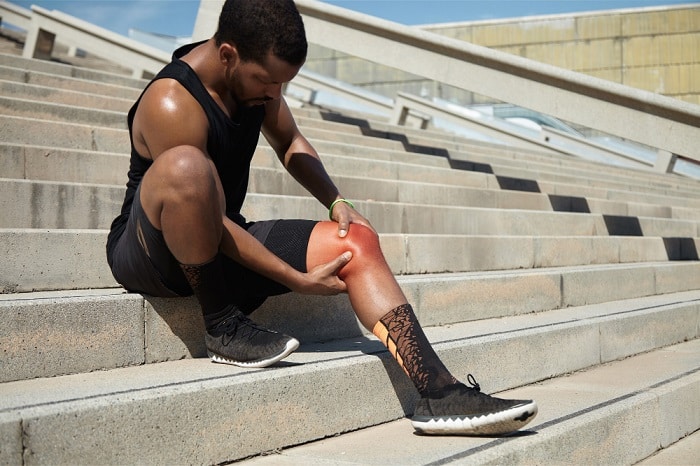 Image of a male athlete grimacing from a leg muscle strain during a workout