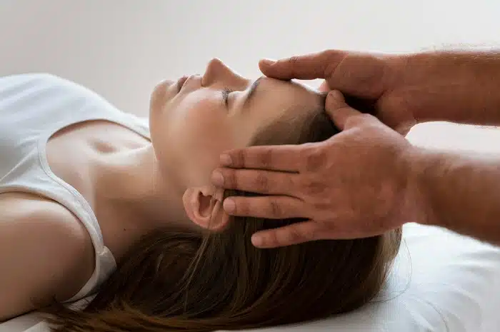 Chiropractor applying gentle pressure on temples to alleviate headache pain